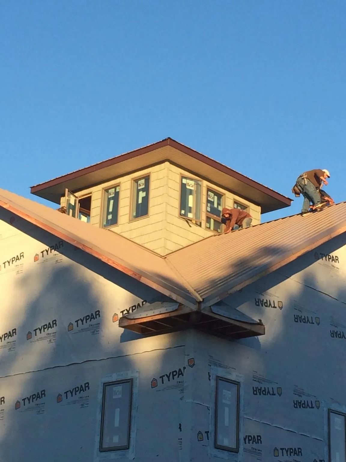 Roofers working around a rooftop cupola on a new metal roof at sunset — Roof Waterproofing in Bellevue by Roofing Brothers